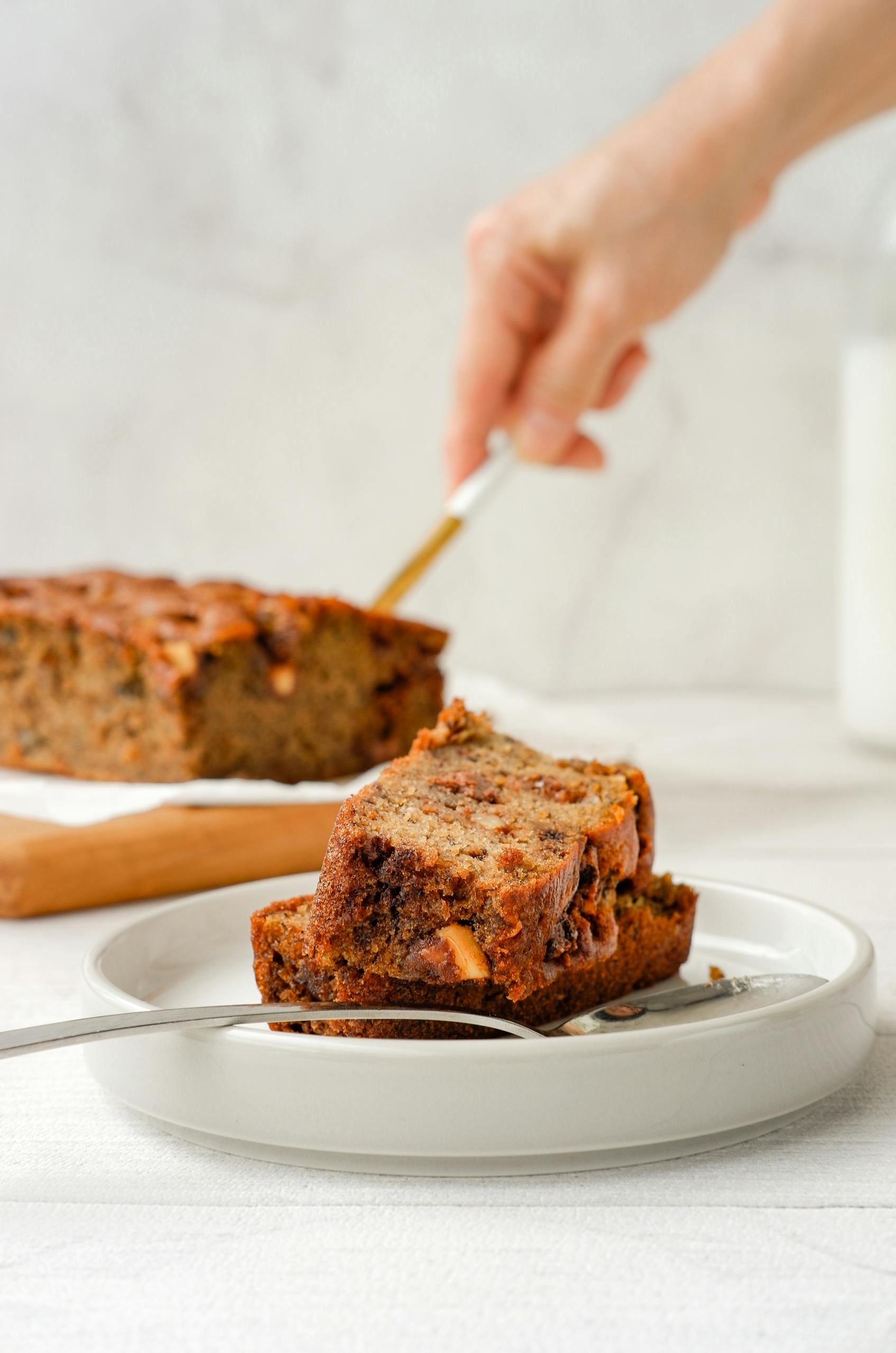 Two slices of homemade banana bread served on a white plate with a blurred background.