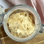 dehydrated sourdough starter flakes in a jar next to a pink towel