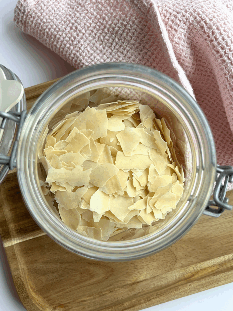 dehydrated sourdough starter flakes in a jar next to a pink towel