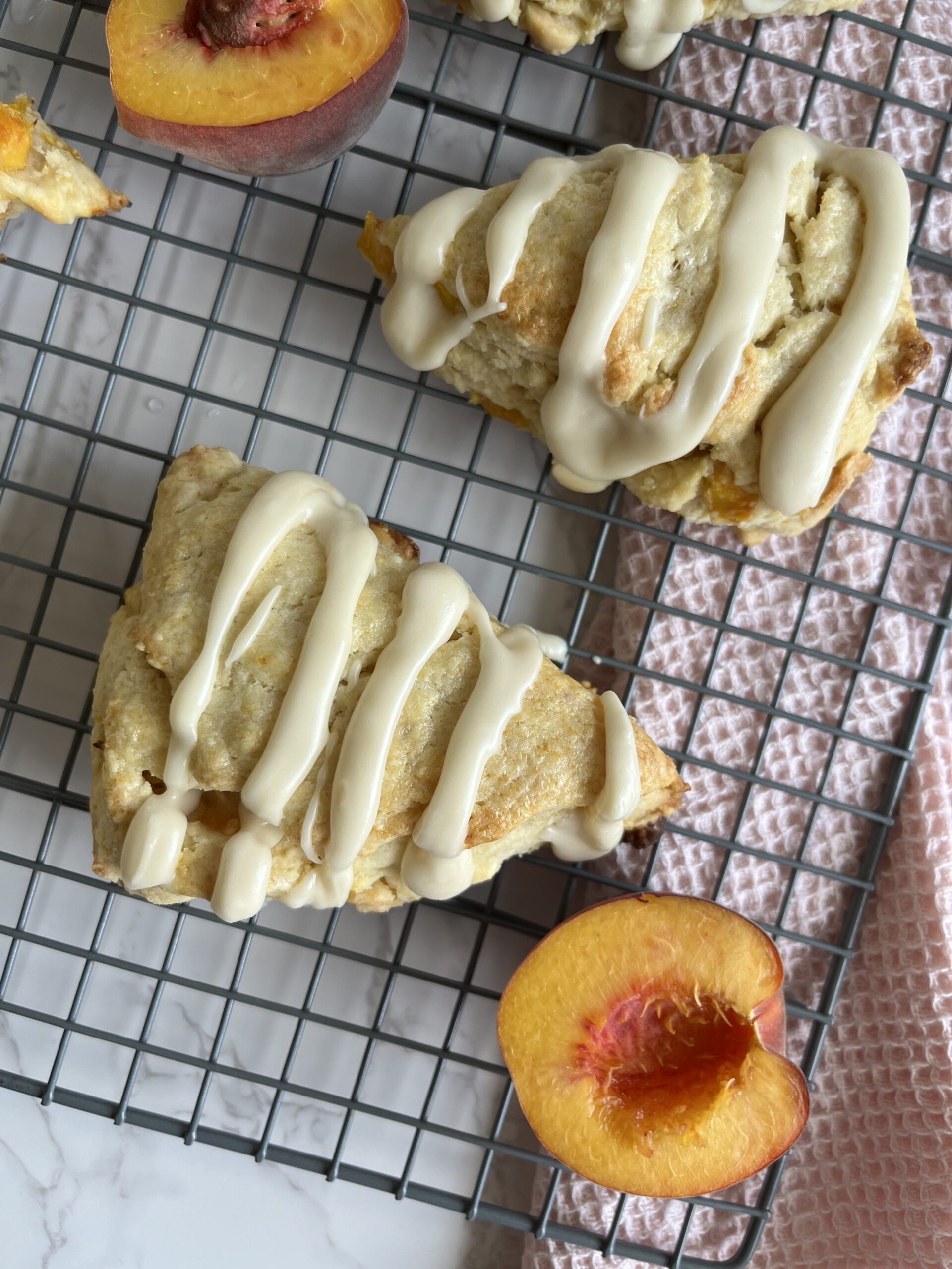 Sourdough Peaches and Cream Scones with halved peached on a wire wrack with pink towel